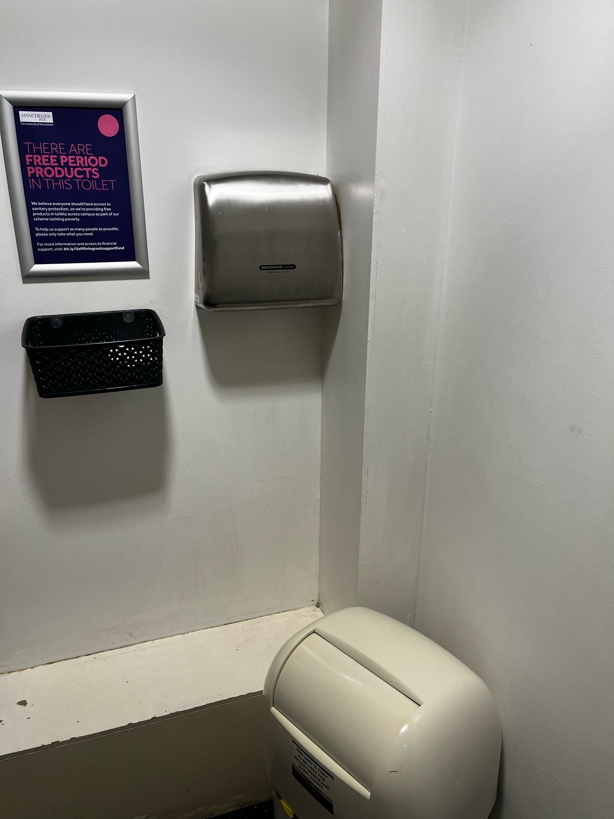 Close up of right side of bathroom, where the sanitary pads, dryer and bin is. Bin is slightly blocking access to dryer.