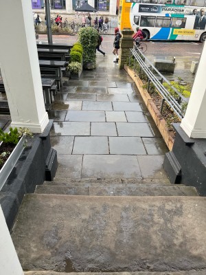 Main entrance of cafe looking inside-out. Ramp leads to outside dining space, followed by four steps lead to inside entrance