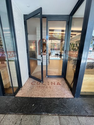 Glass doors with black metal frame and silver handle. Pull right door from middle.