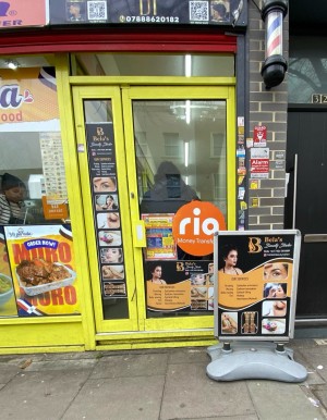 Glass door with yellow frame ahead. Standing sign on right obstructing entrance.