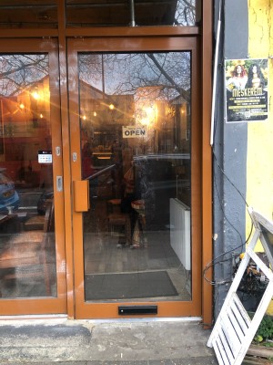 Glass door with brown frame. Push handle on left to open.