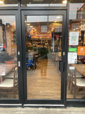 Glass door with black frame ahead. Pull door to open via handle on right.