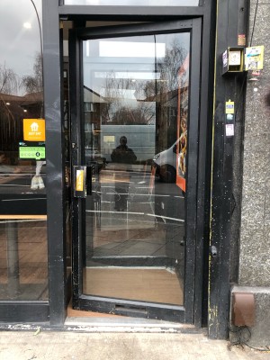 Glass door with black frame. Push handle on left to open.