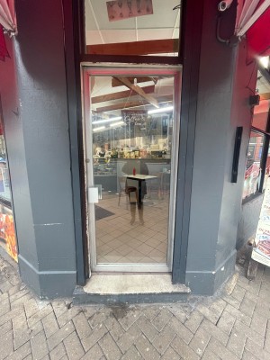 Glass door ahead with metal frame ahead. Push silver metal handle on left to open.
