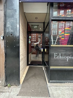 Opening ahead leads to glass door with black frame at back. Pull black metal handle on right to open.