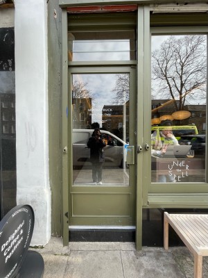 Green metal-framed glass door ahead. Push from metal handle on right to open.