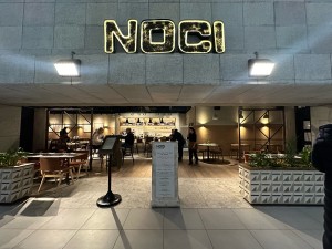 Opening ahead. Welcome desk and standing menu in centre. Planters to left and right.