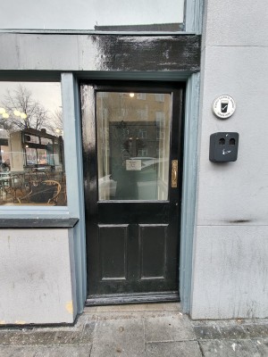 Black preceding glass door. Push golden handle on right to open.