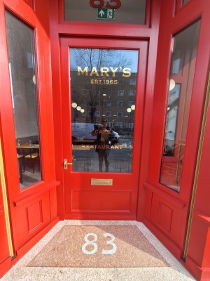Red door with glass panel ahead. Push gold handle on left to open.