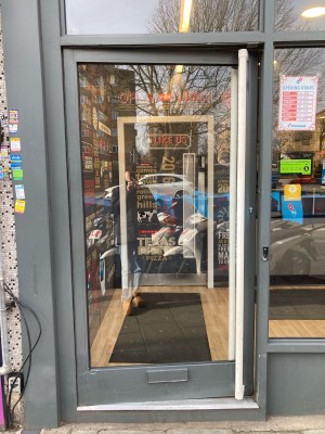 Glass door with grey frame ahead. Push door to open via handle on right.