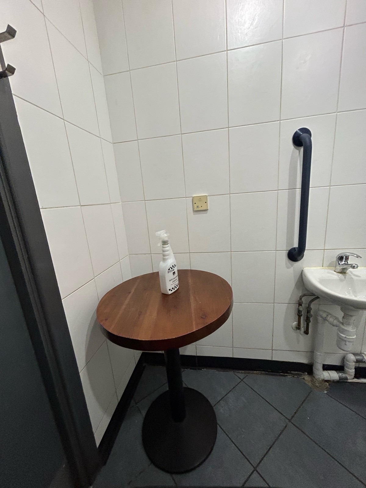 Table in the left corner next to the door with cleaning spray