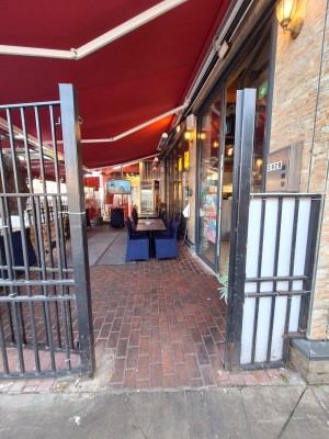 From pavement facing venue. Black gate ahead. Push on right to open.