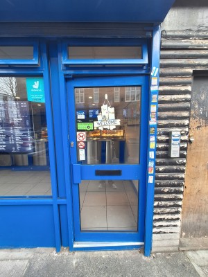 Glass door with blue frames ahead. Push on left to open.