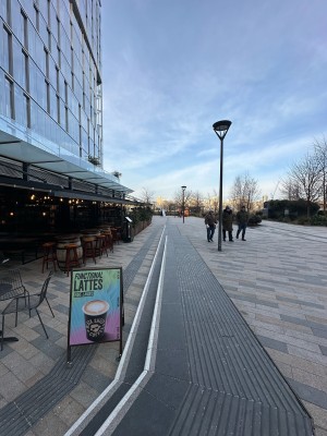 From top of steps in front of venue facing right. Ramp down ahead. Steps down along right.