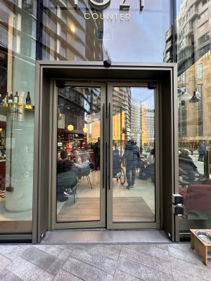 Glass doors with brown frame. Push black handles in centre to open. Dog bowl to right.