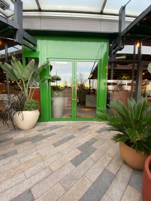 Glass doors with green frames ahead. Pull from handles in centre to open.