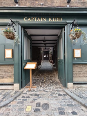 Green framed preceding doors. Push from centre to open. Wait sign on left obstructing path.