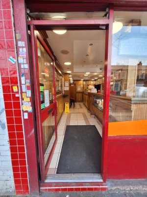 Glass door with red frames. Push on right to open.
