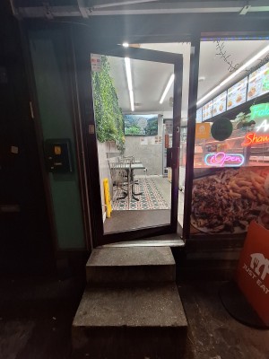 Glass door with red frames. Push on right to open. Bump at door threshold. Doormat after.