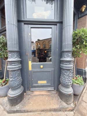 Grey door with glass panel ahead. Push on left to open.
