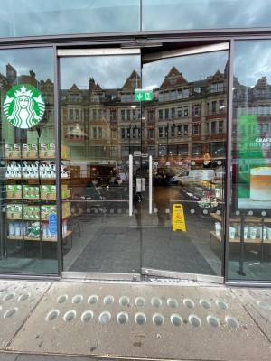 Glass doors with metal frame ahead. Push sliver handles from center to open.