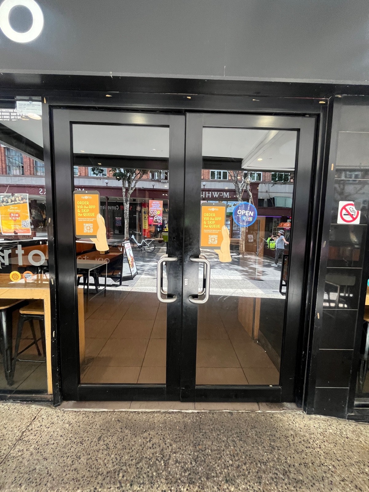 Glass doors with black metal frames and silver handles in middle. Pull to open.