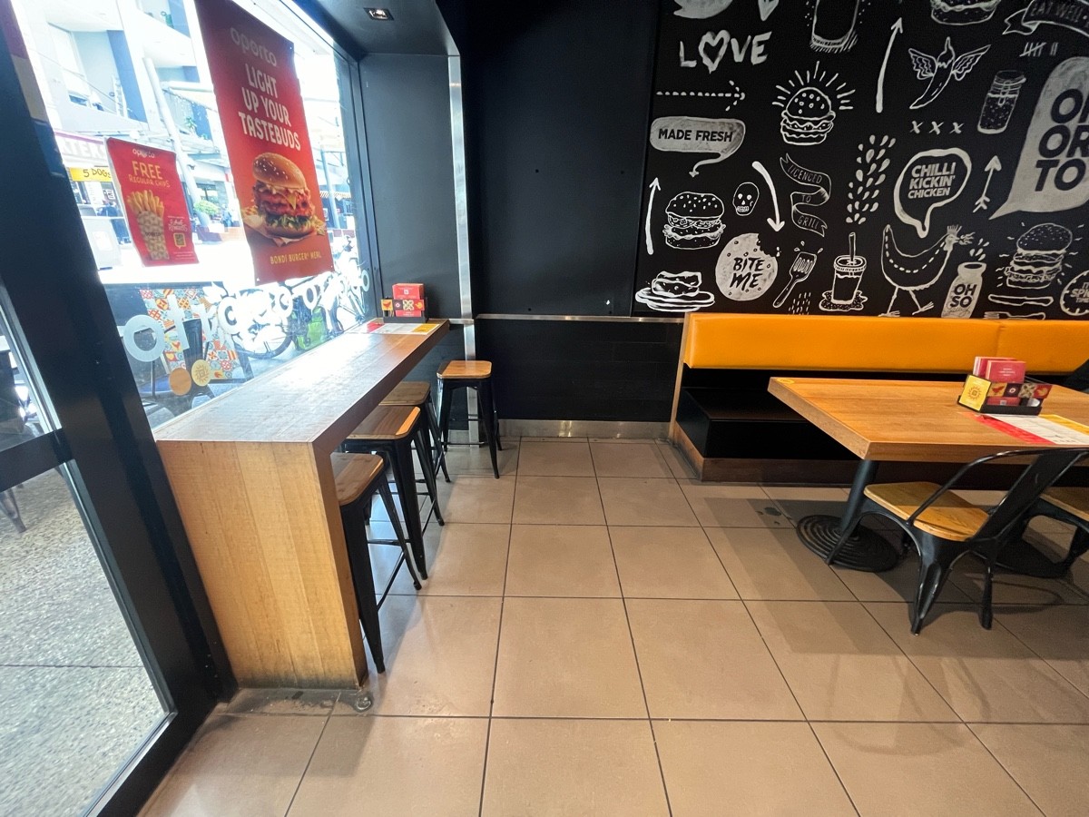 From entrance facing left. High table and backless stools on left wall. Half booths ahead to right.
