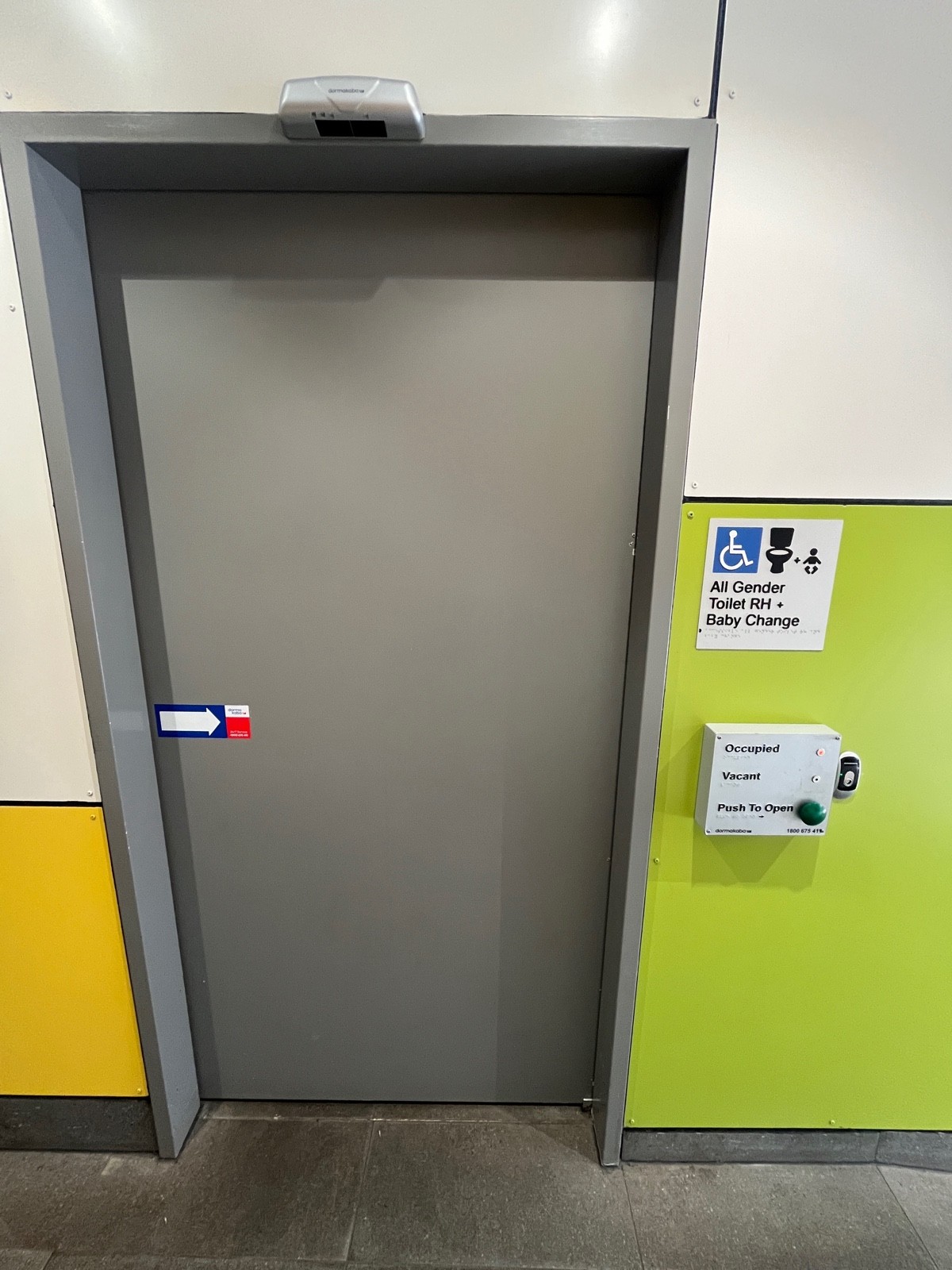 From top of ramp facing right. Grey wooden bathroom door slides open to right. Push button on wall to right.
