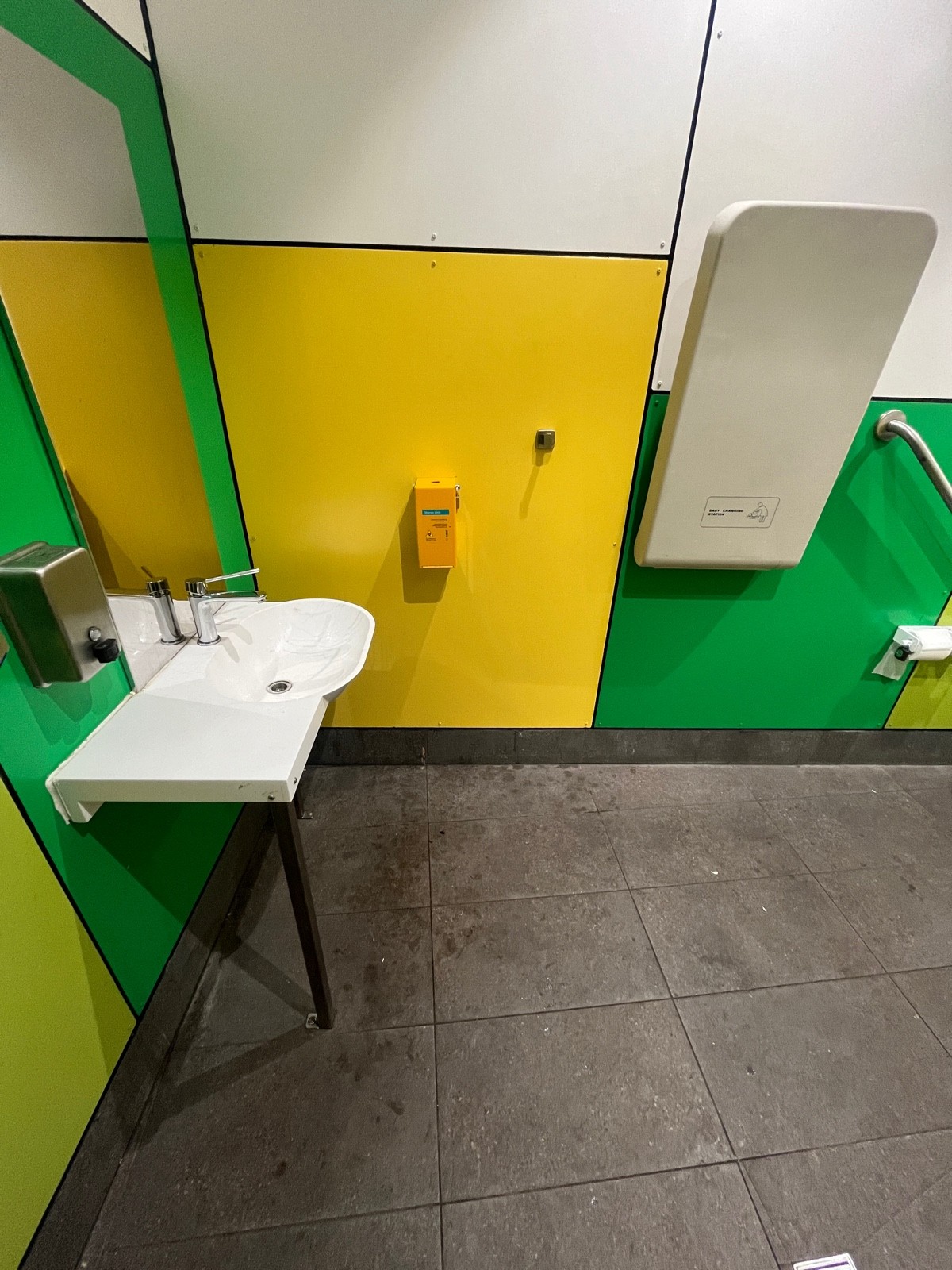 From door facing straight. Sink on left wall. Seated height hook on wall ahead. Baby change on wall ahead to right.