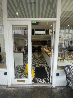 Glass doors with white frame ahead. Push gold metal handle in centre to open.