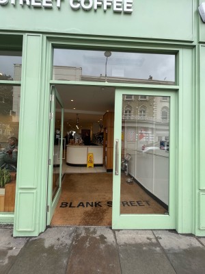 Facing glass doors with mint green frame. Push silver handles in center to open.