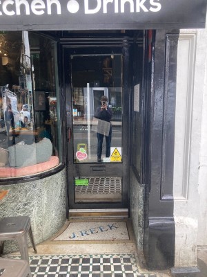 Black wooden door with glass panel ahead. Pull handle on left to open.