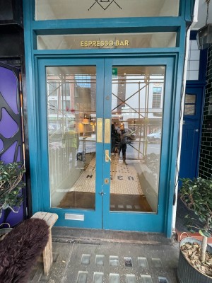 Glass doors with blue frame. Push brass in center right to open.