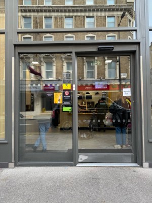View of main entrance from street. Single glass automatic door that leads directly towards counter