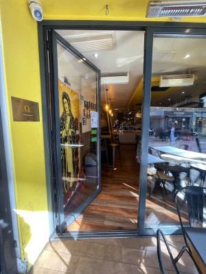 Glass door with black frame ahead. Push black metal handle on right to open.