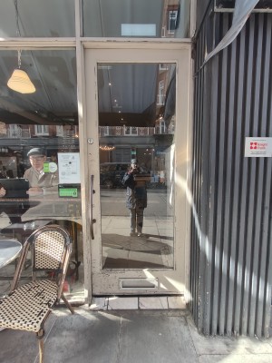 White framed glass door. Push silver handle on left to open.