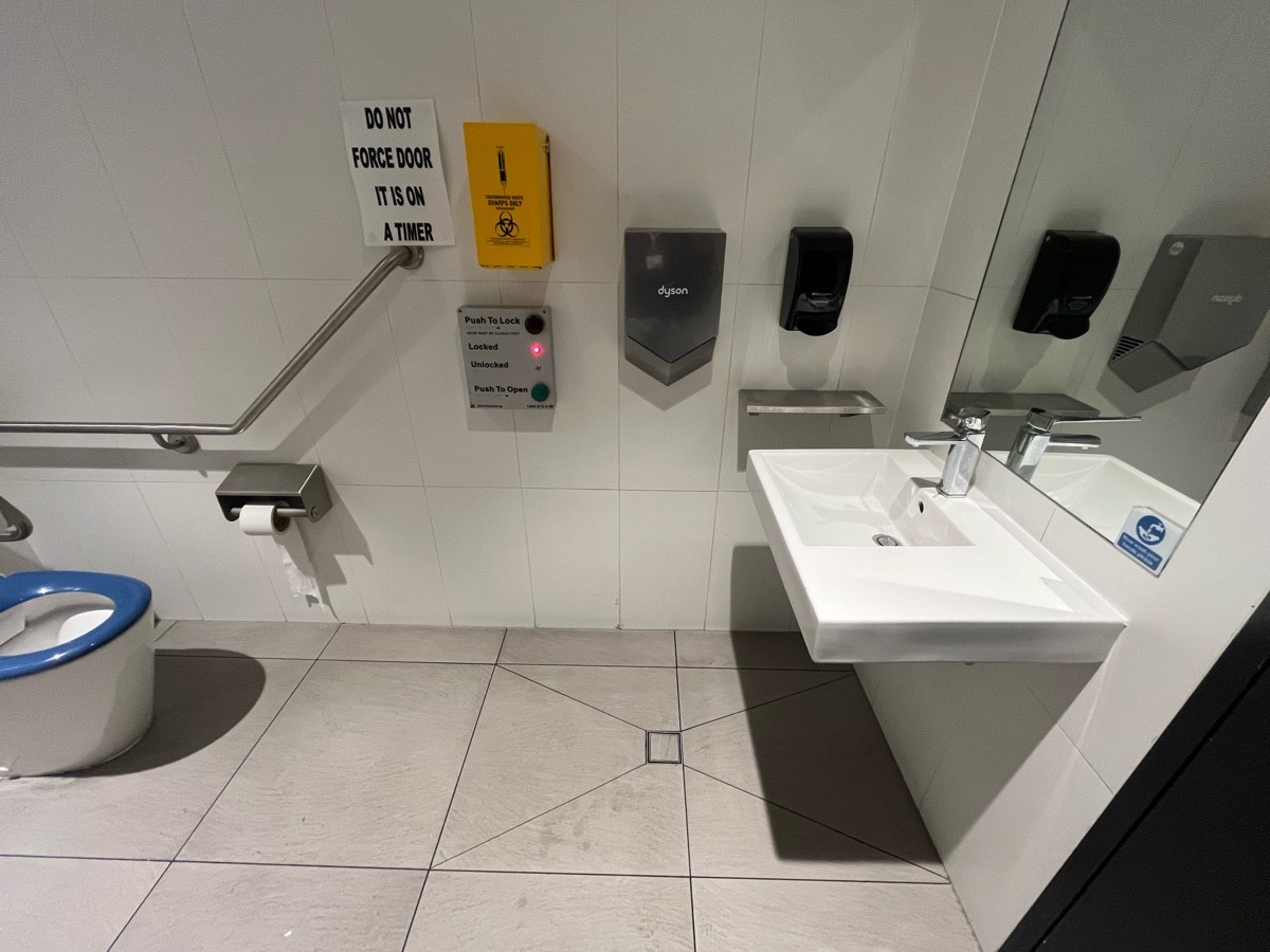 From door facing right. Buttons to lock and open on wall ahead. Sink on right wall.