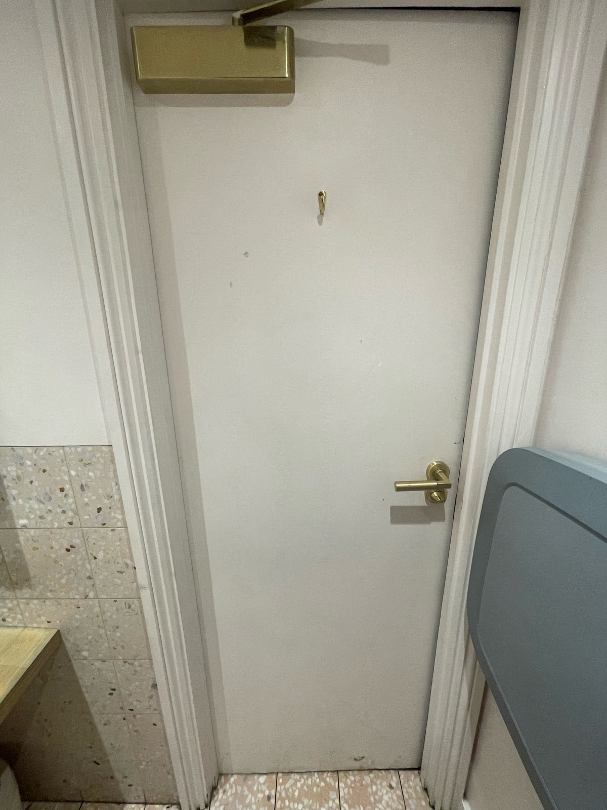 Back of bathroom door. Hook in top centre. Push gold metal handle on right to open.