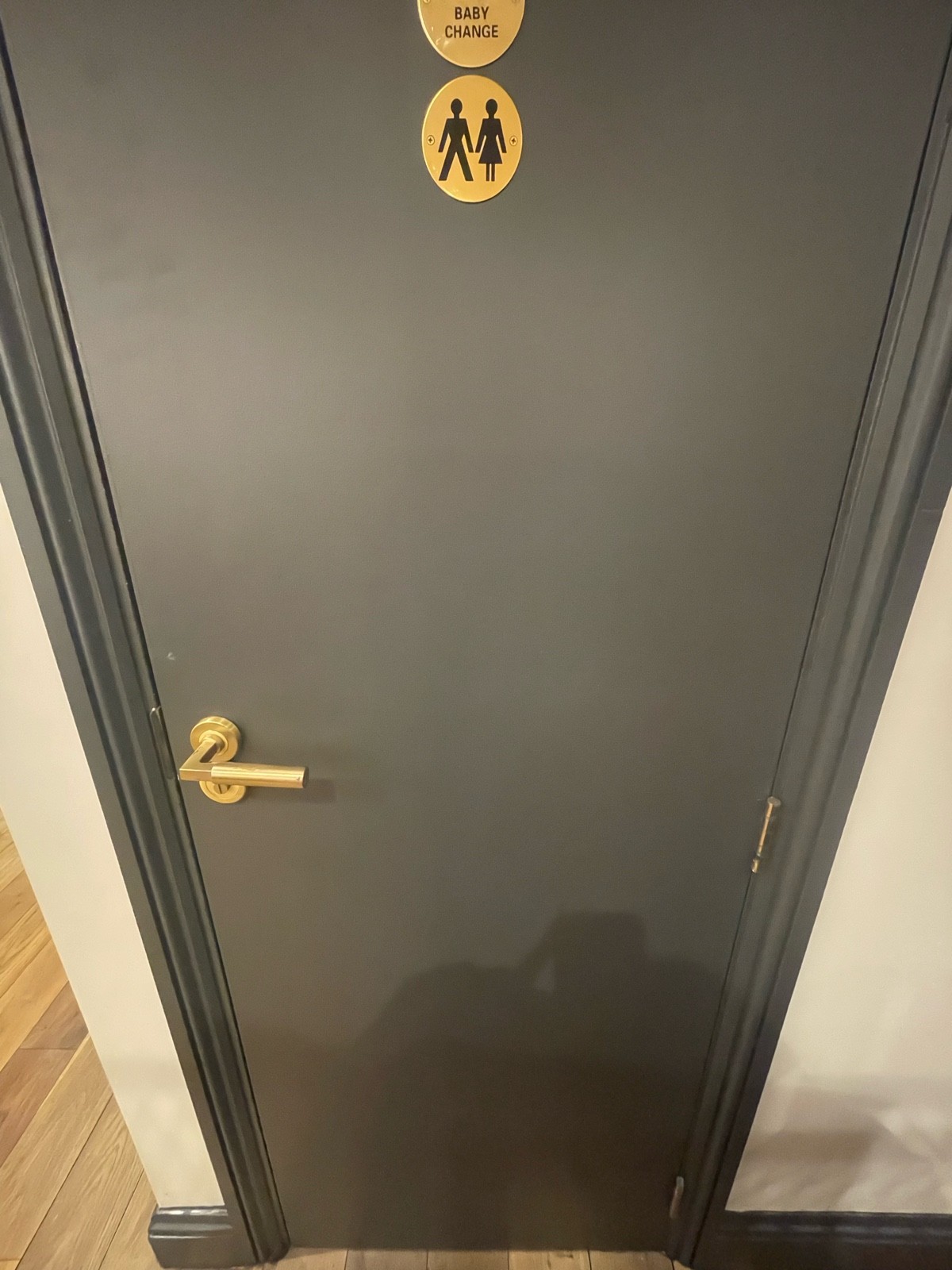 From before first door facing straight. Black wooden door ahead. Pull gold metal handle on left to open.