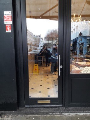 Glass door with black frames. Push on right handle to open.