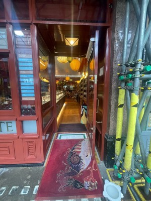 Glass door with brown frame ahead. Pull gold metal handle on left to open. Dog bowl on right.