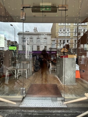 Glass door ahead with silver metal handle on left. Push to open.