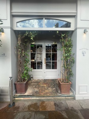 From street facing venue. Opening ahead. Step up at foot of opening. Planters on left and right after step.