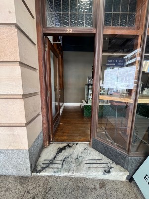 Door with brown wooden frame and gold metal handle on right. Push to open.