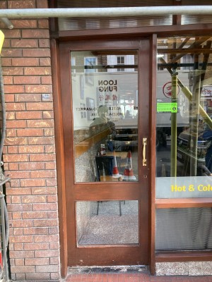 Glass door with wooden frame ahead. Push to open via brass handle on right.