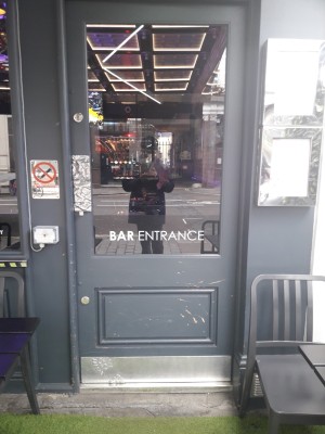 Grey door with glass panel ahead. Push on left to open.