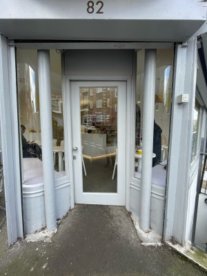 Grey wood-framed glass door ahead. Push from silver handle on left to open.