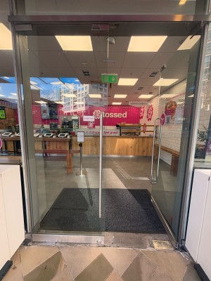 From outside area facing straight. Double glass doors ahead. Push metal handles at center of door to open.