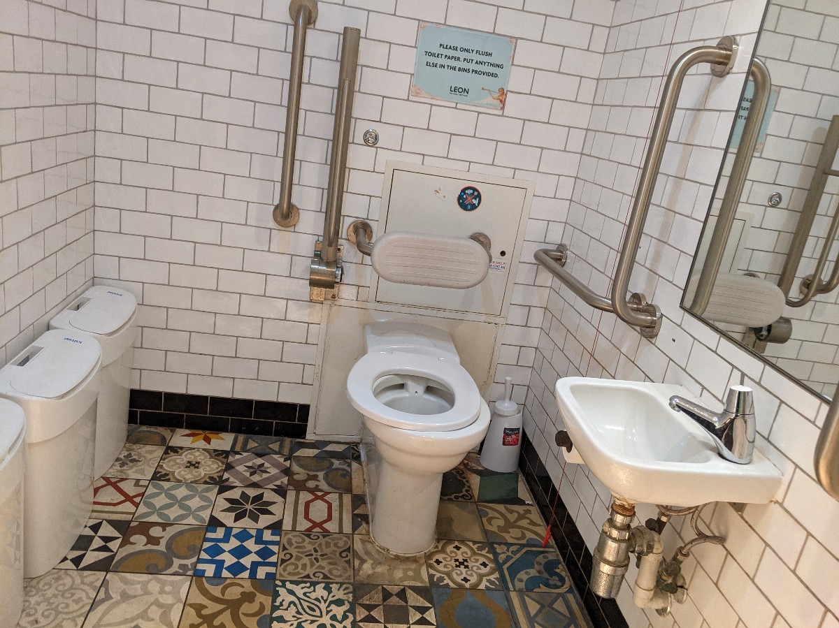 From second door facing left. Bins on left, toilet ahead back. Emergency pull cord right of toilet. Sink on right wall.