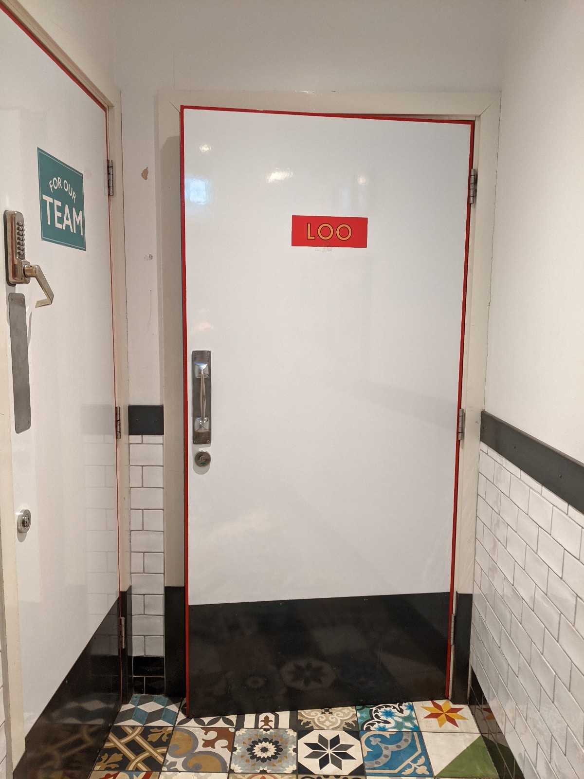 From first door facing straight. White door with white frame ahead. Pull from metal handle on left to open.